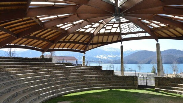 Un amphithéâtre extérieur abrité, doté de gradins en pierre et offrant une vue sur un lac et des montagnes.