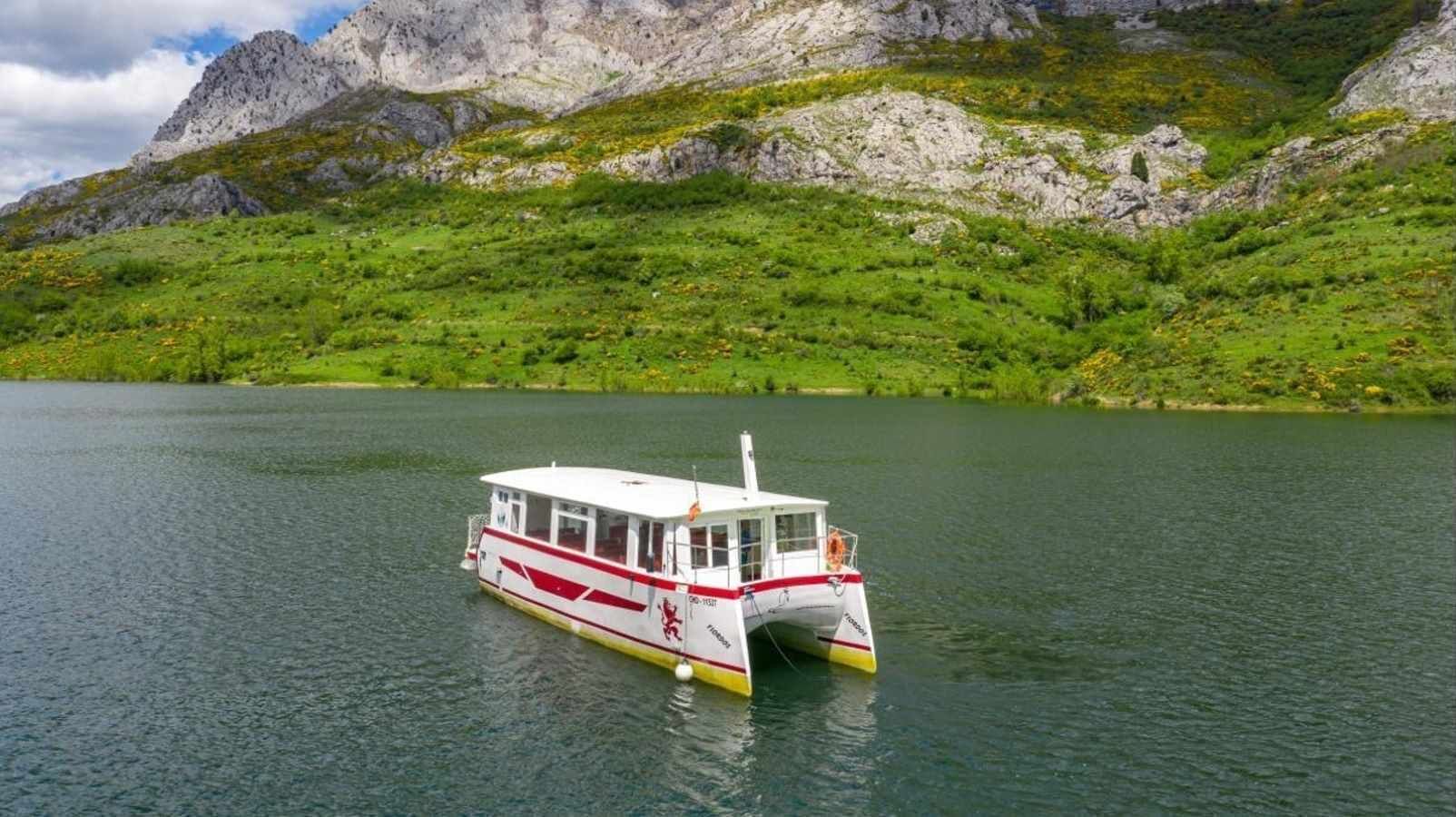 Un bote en un lago con montañas al fondo.