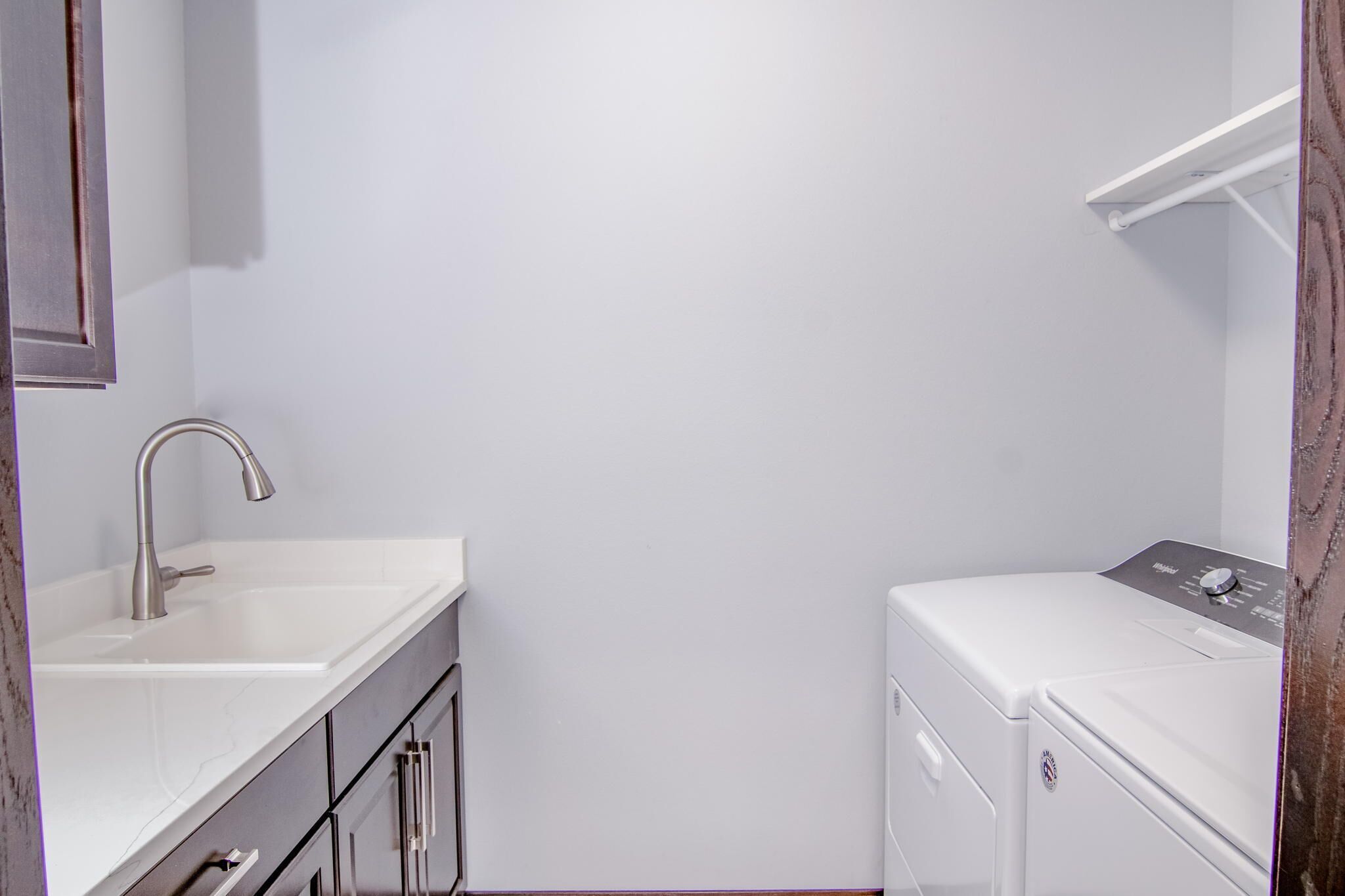 A small, clean laundry room with a white washing machine and a sink.