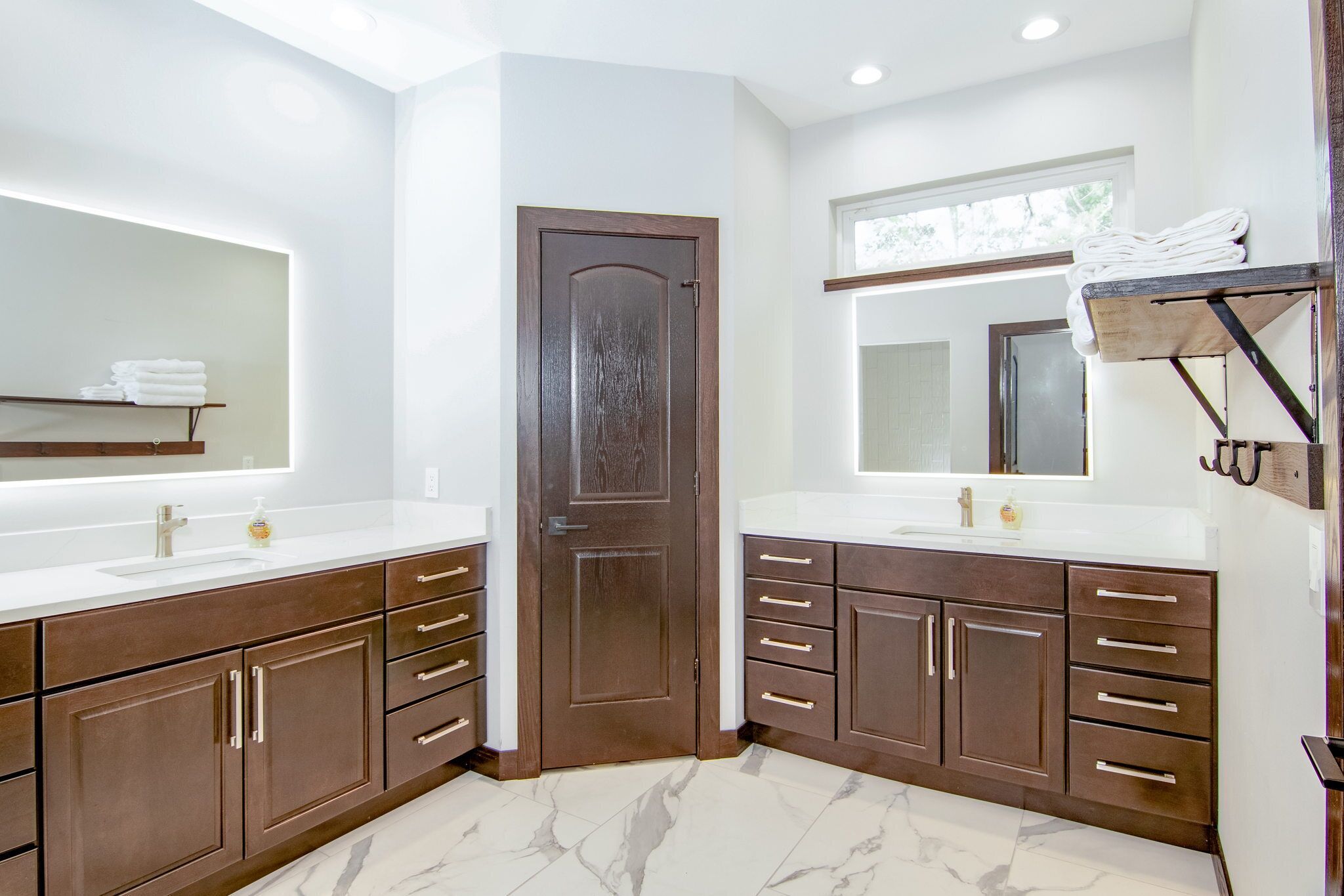 A modern bathroom with two sinks, dark wooden cabinets, and a large mirror.