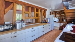 Een moderne keuken met houten balken, een inbouwoven, een koffieapparaat en een koelkast.