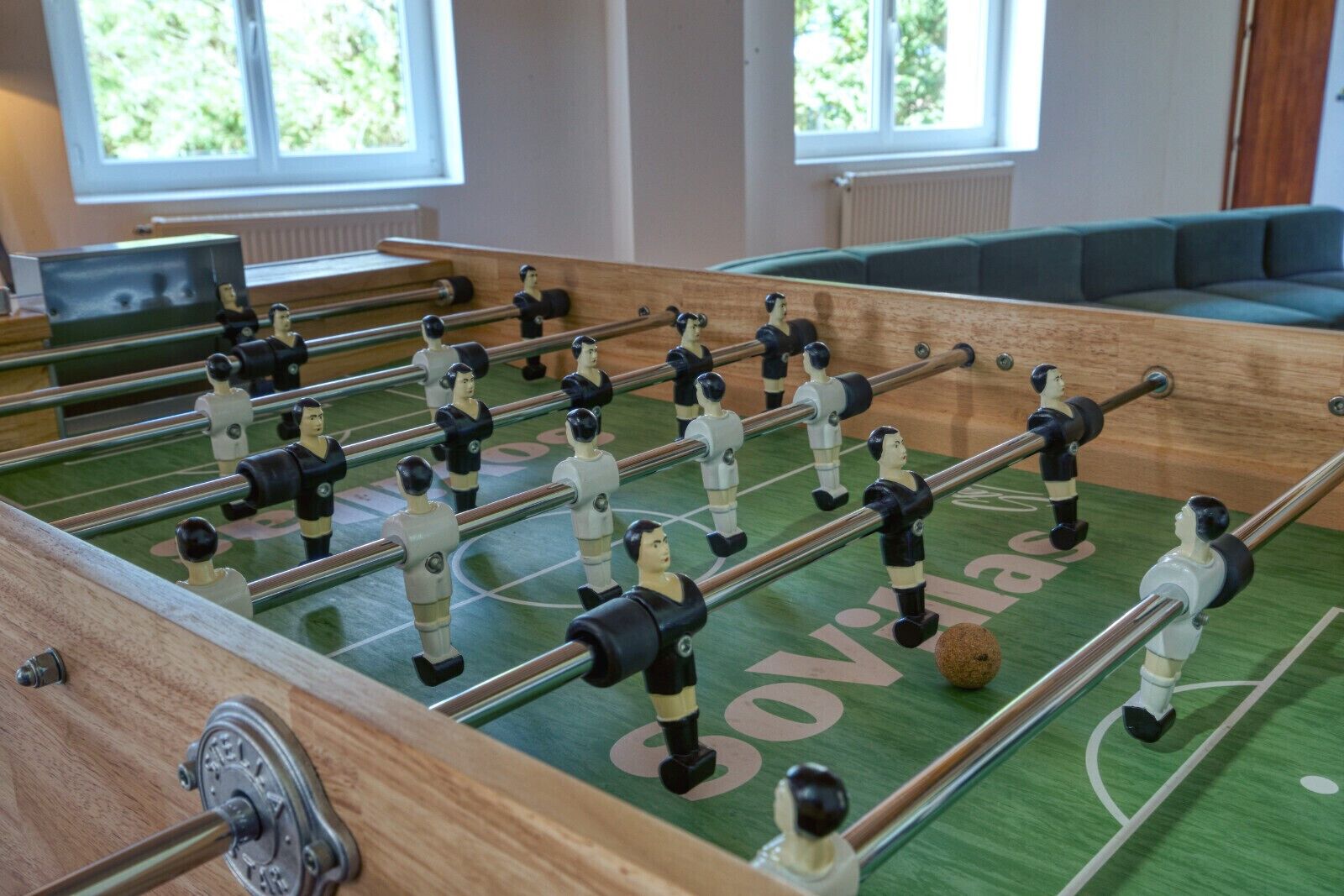 Una mesa de fútbolín con superficie de juego verde y la palabra 'Sovias' escrita en ella.