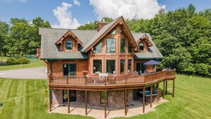 A large log cabin with a spacious deck and multiple windows. - Dog Friendly Luxury Estate w/ Hot Tub & Dock (Oakland)