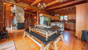 A spacious log cabin interior with a large wooden dining table, stone fireplace, and modern kitchen appliances. - Dog Friendly Luxury Estate w/ Hot Tub & Dock (Oakland)