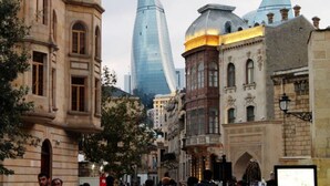 A street with historic buildings, including a prominent modern glass skyscraper and traditional architecture. - Diva Hotel (Baku)