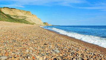 Enjoy a serene beach experience with a gentle slope leading up to a natural cliff and a calm sea.