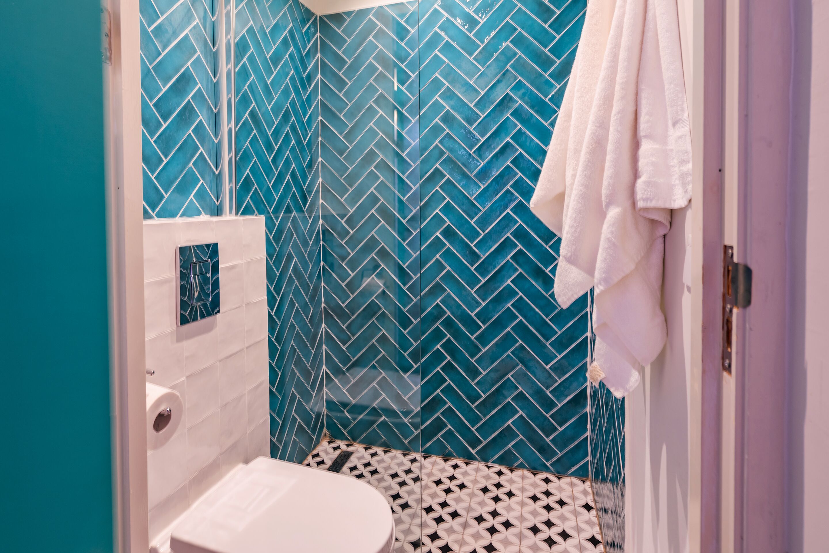 A bathroom with a white toilet, a white sink, and a shower area with blue patterned tiles.