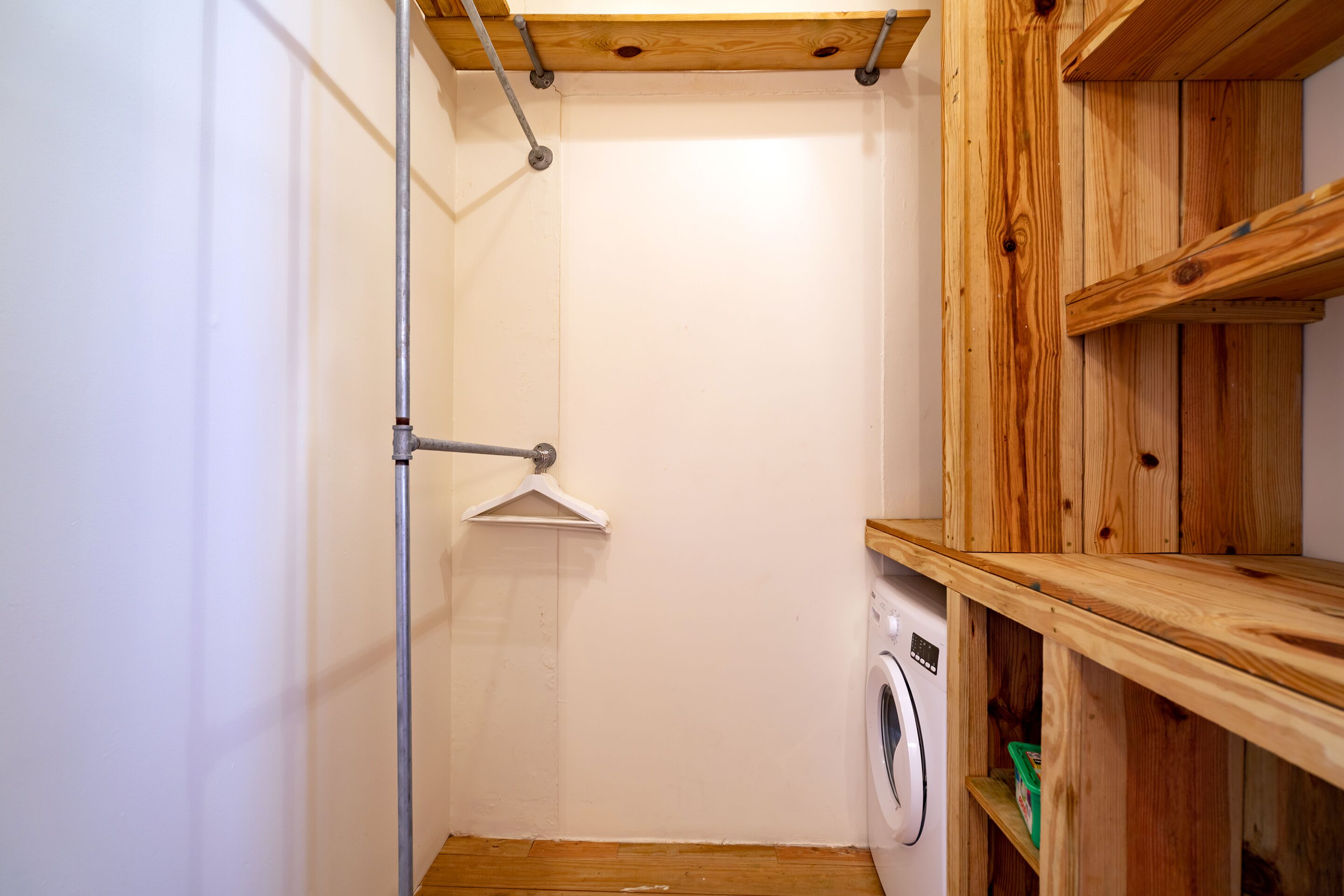 Un bagno funzionale con lavatrice, mensole in legno e porta asciugamani in metallo.