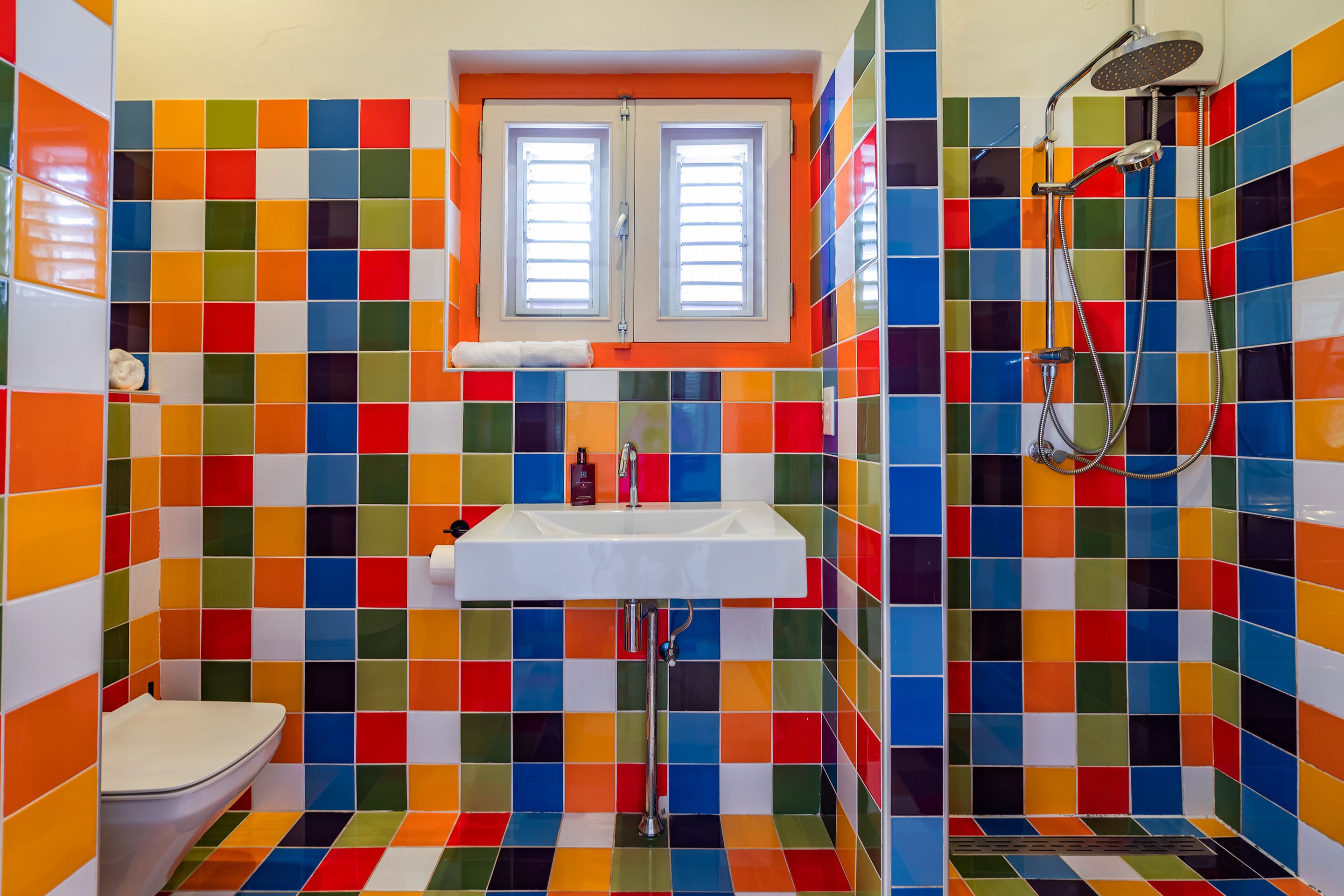 Un baño con azulejos de colores, un lavamanos, un inodoro y una ducha.
