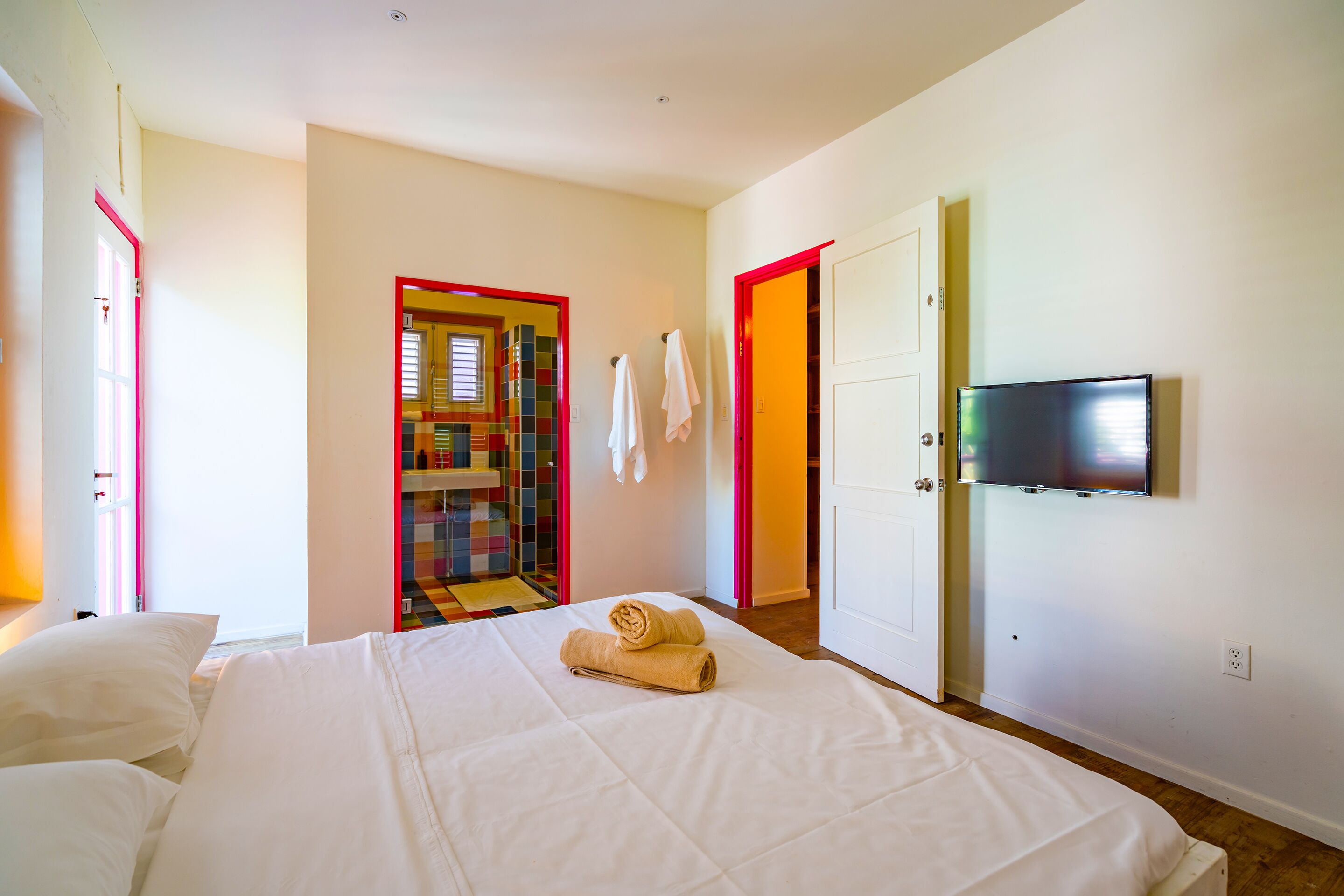 A hotel room with a bed, a TV mounted on the wall, and a door leading to a bathroom.