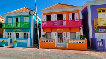 A row of colorful boutique hotels with balconies and potted plants.
