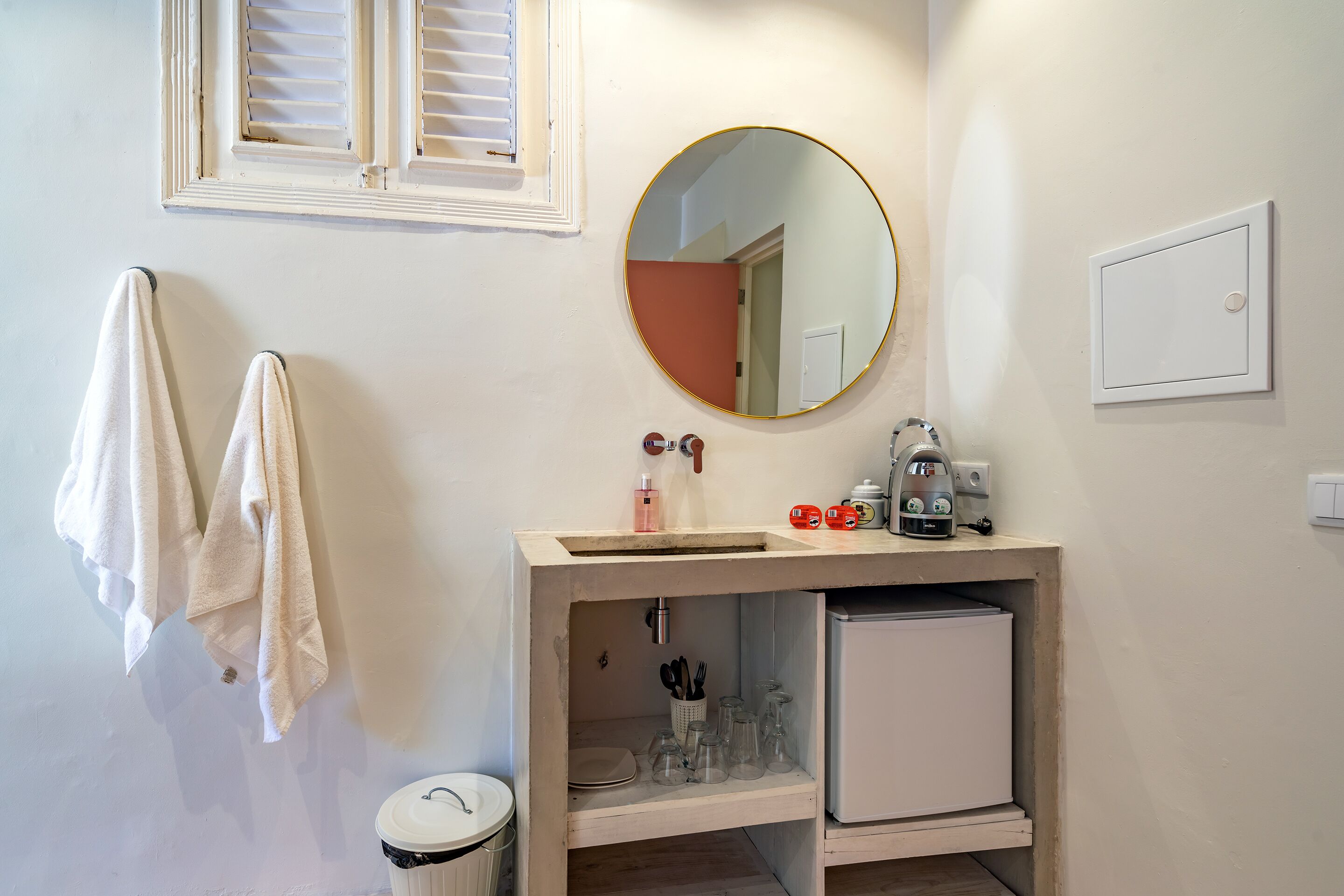 Un baño con lavamanos, espejo, toallero y un mueble pequeño.