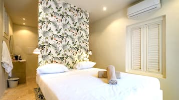 Una habitación de hotel con cama, baño y ventana con contraventanas.