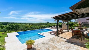 Ein Pool mit einer Steindeck, Liegestühlen und einer Pergola.