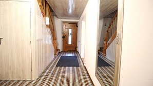 A hallway with patterned flooring, a wooden door at the end, and a blue mat at the entrance.