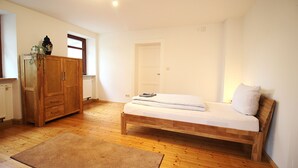 A bedroom with a wooden bed, a wardrobe, and a radiator.