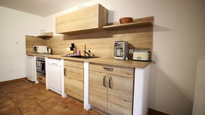 A compact kitchen with wooden cabinetry, a dishwasher, a microwave, and a toaster.