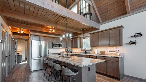 A spacious kitchen with a large island, bar stools, and wooden beams on the ceiling.