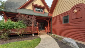 A two-story house with a porch, a stone pathway, and a large rock in the front yard. - Hot Tub, Fire Pit & Theater Room by Deep Creek (McHenry)