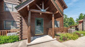 A log cabin with a porch, a number '6' sign, and a view of the surrounding area.