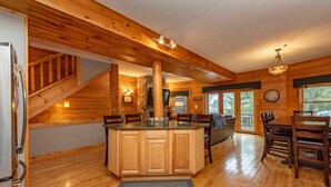 A wooden interior with a kitchen island, dining table, and chairs.