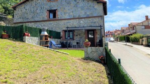 A stone house with a patio, a barbecue grill, and a small garden area. - Las Hortensias Country House in Hoznayo (Santa Marina (Entrambasaguas))