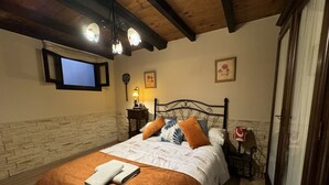 Ein Schlafzimmer mit einem Bett, einem an der Wand montierten Fernseher, einer Lampe und einem gerahmten Bild.