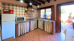 A kitchen with a microwave, oven, and sink, featuring a checkered tile backsplash and wooden beams. - House (Llanes)