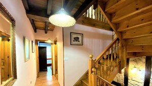 A wooden staircase with a stone wall and a hanging light fixture. - House (Llanes)