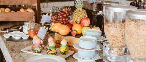 A breakfast buffet with various fruits, pastries, and beverages.