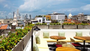 A rooftop terrace with outdoor seating, a view of the city skyline, and a clock tower. - Hotel Voilá Centro Histórico (Cartagena)