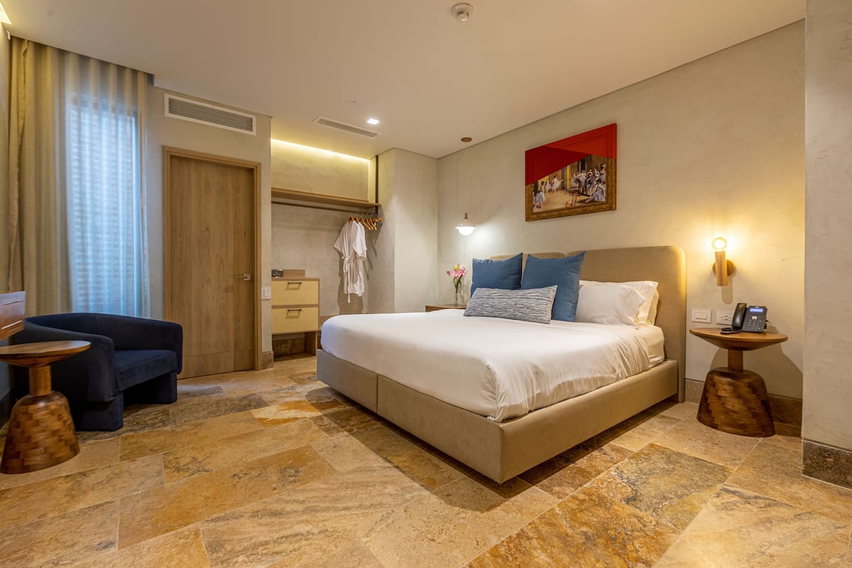 Ein Hotelzimmer mit einem großen Bett, einer Couch, einem kleinen Tisch und einem Spiegel.