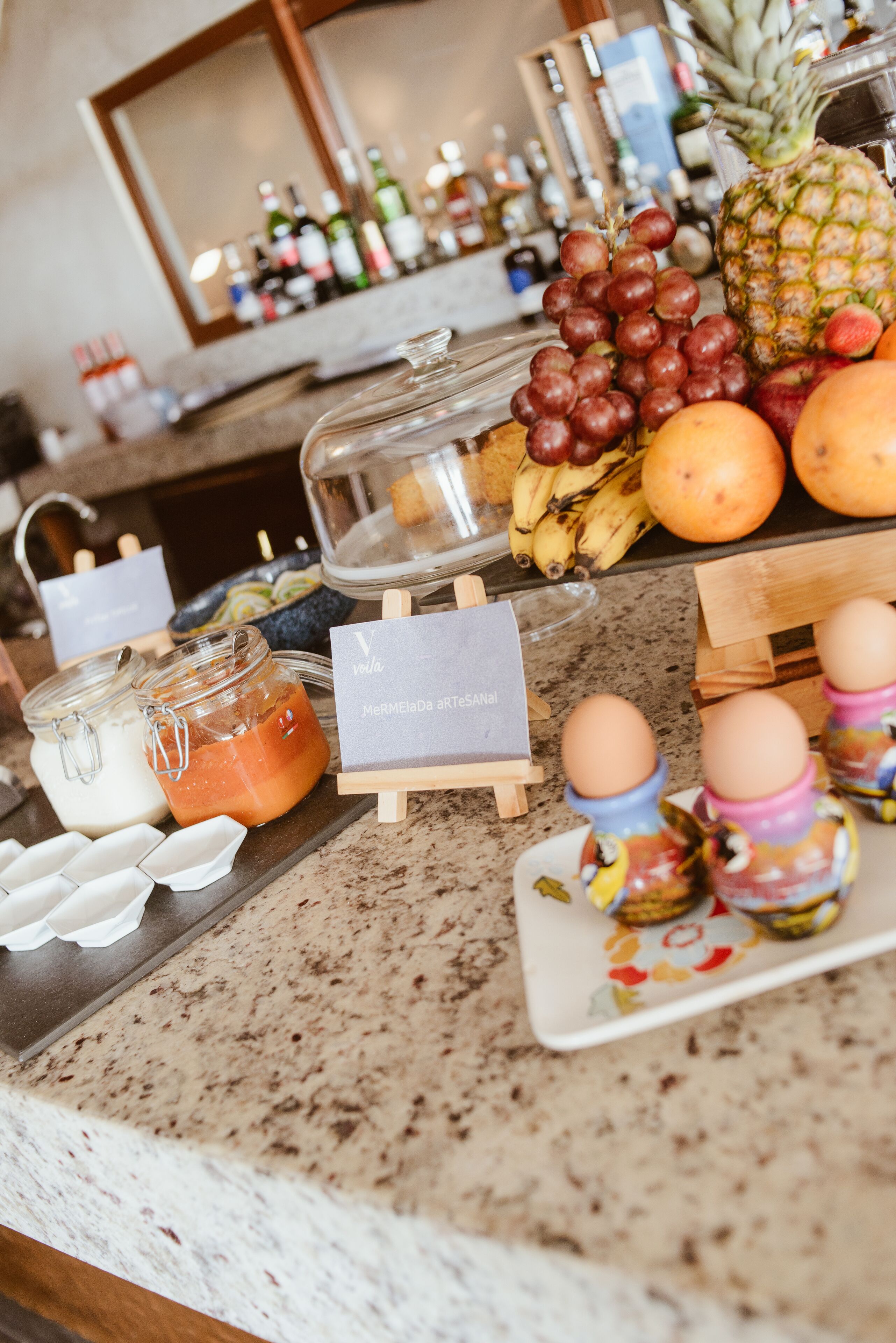 A kitchen counter with various food items, including fruits, eggs, and condiments.