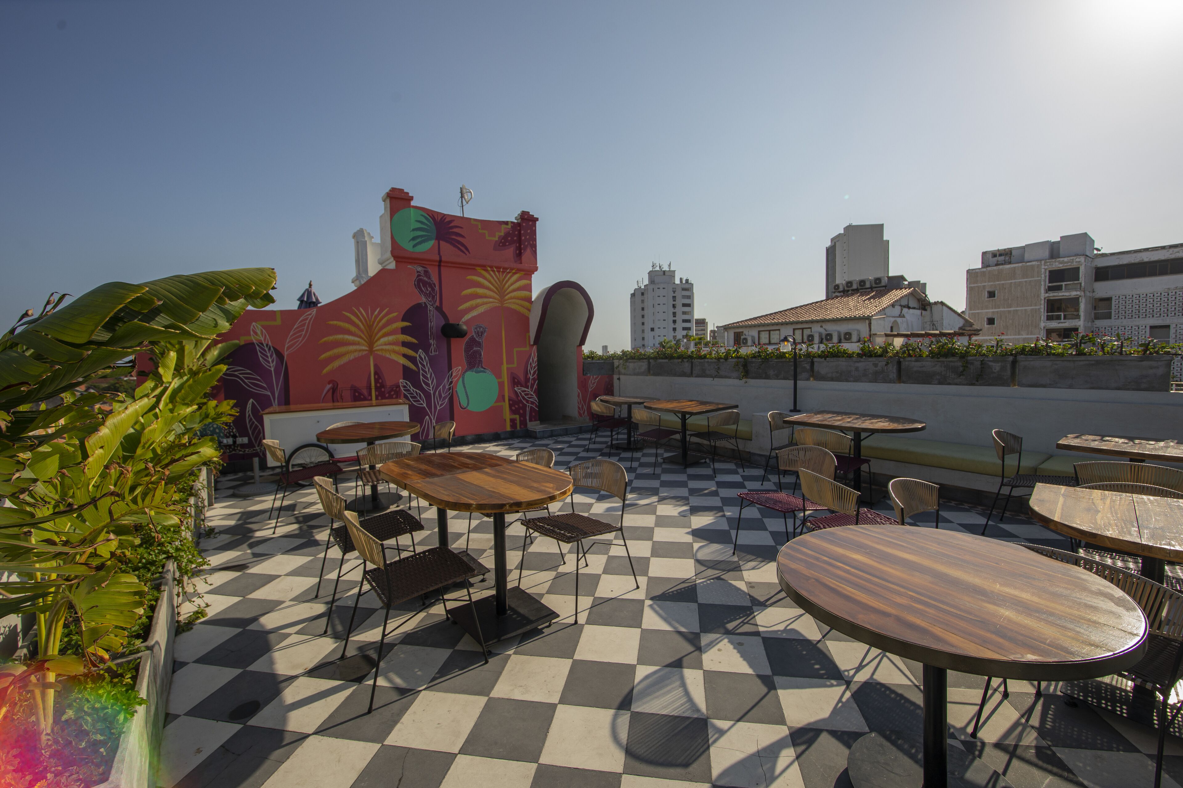 Une terrasse sur le toit dotée d’un sol à carreaux, de sièges extérieurs et d’une fresque murale colorée.
