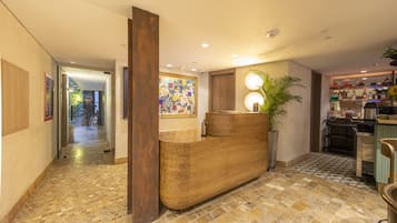 Una zona de recepción con un mostrador de madera, un cuadro abstracto de gran tamaño y suelo de baldosas.