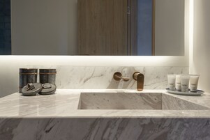 A bathroom with a marble sink, a wooden door, and a mirror.