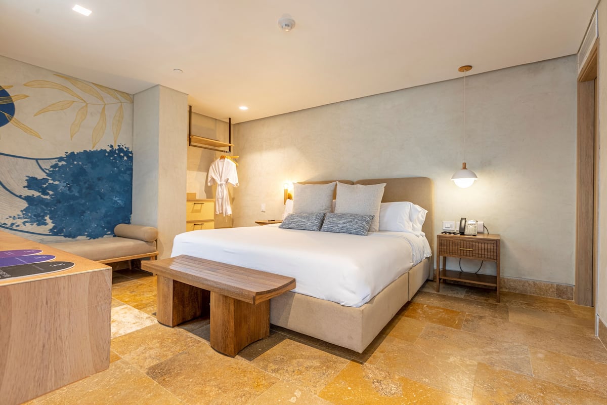 Ein modernes Schlafzimmer mit einem großen Bett, Nachttischen, einer Bank und einer Wandmalerei.