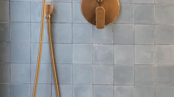 A shower with a handheld showerhead and a wall-mounted control valve.