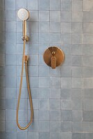 A shower with a handheld showerhead and a wall-mounted control valve.