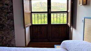Una stanza con una porta in legno che dà su un balcone con vista sulle montagne.