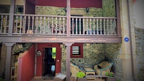 Un edificio a due piani con un balcone, pareti in pietra e posti a sedere all'aperto.