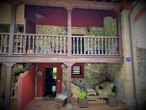 Een gebouw met twee verdiepingen, een balkon, stenen muren en een terras.