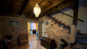Ein gemütliches Interieur mit Kamin, einer Holztreppe und Korbmöbeln.