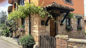 A stone building with a wooden door, a small porch, and a brick wall.