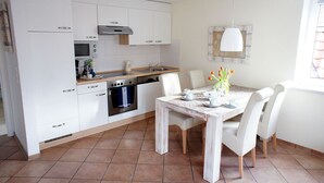 Una cocina moderna con armarios blancos, horno empotrado y una mesa de comedor para cuatro.