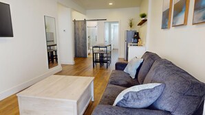 Un soggiorno moderno con un divano grigio, un tavolino in legno e un'area pranzo sullo sfondo.