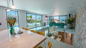 A modern dining area with a large table, yellow chairs, and a view of the ocean through large windows. - Villa Lydia ,two pools, indoor heated pool , sea view (Κίσσαμος)