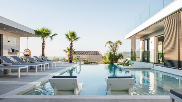 A modern pool area with lounge chairs and palm trees. - Villa Lydia ,two pools, indoor heated pool , sea view (Κίσσαμος)