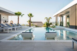 A modern pool area with lounge chairs and palm trees.