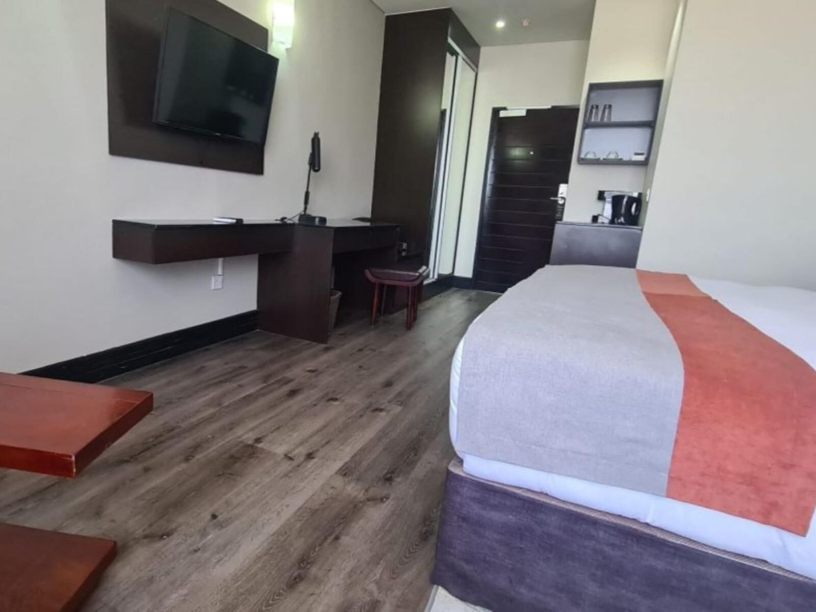 A hotel room with a bed, a desk, a TV, and a staircase.